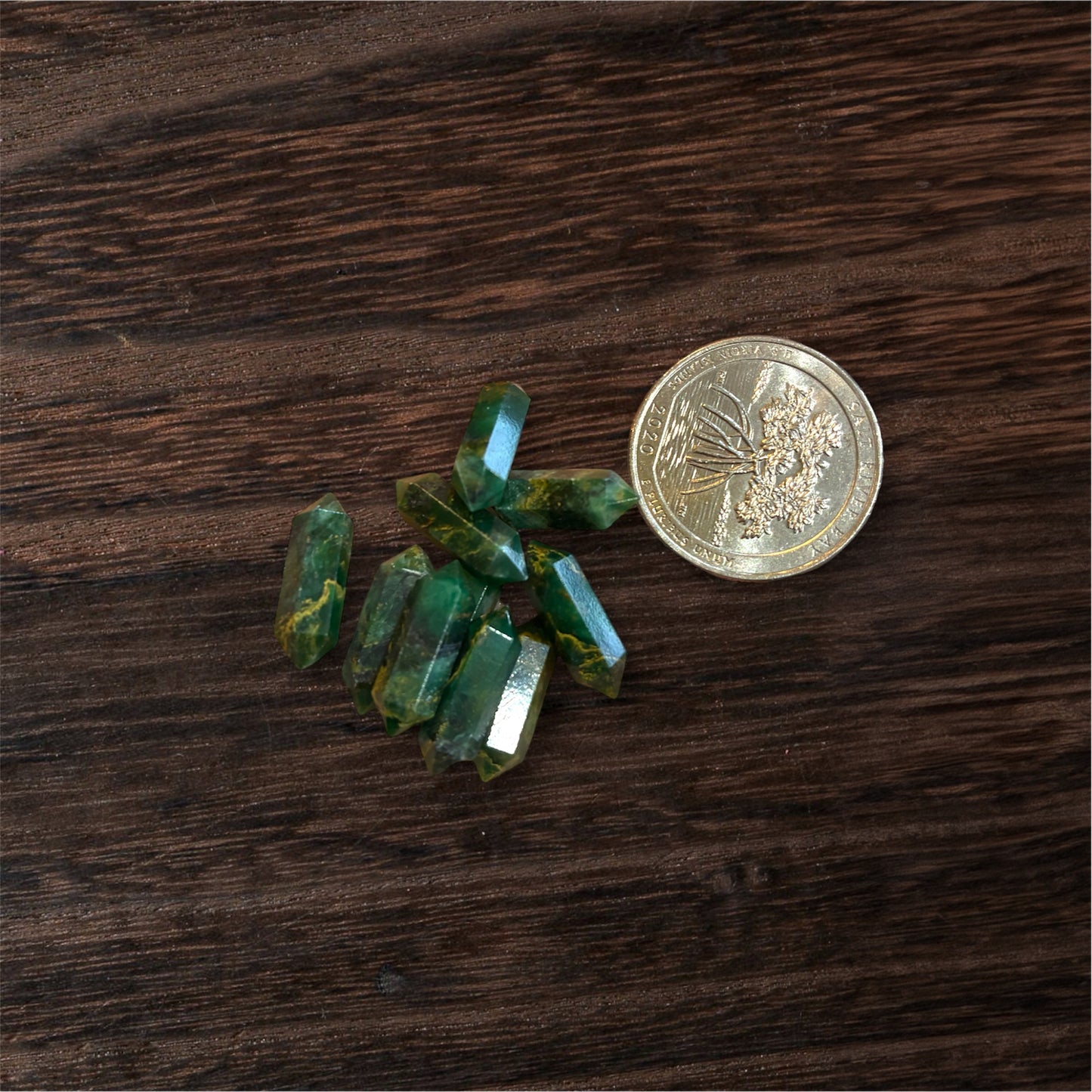 Green crystals and a coin on a wooden surface
