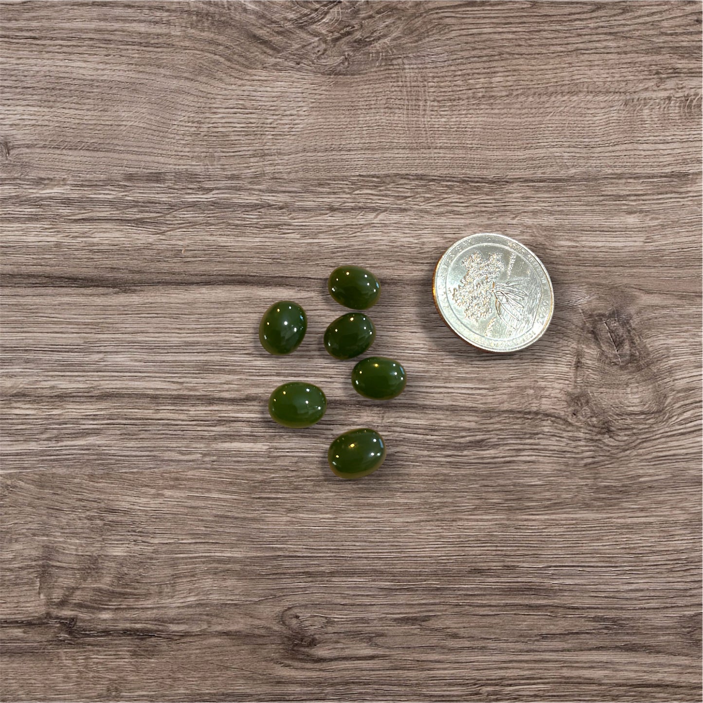 Green stones on a wooden surface with a coin for scale