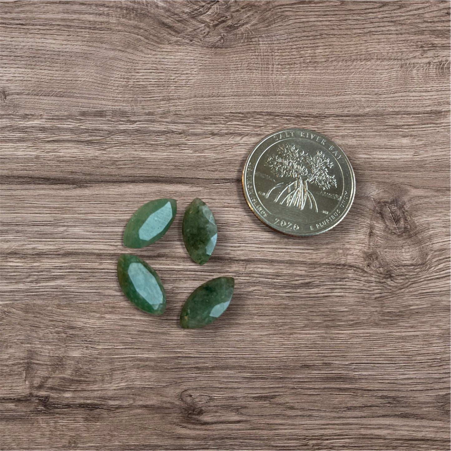 Three green stones on a wooden surface with a coin for scale.