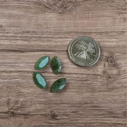 Three green stones on a wooden surface with a coin for scale.