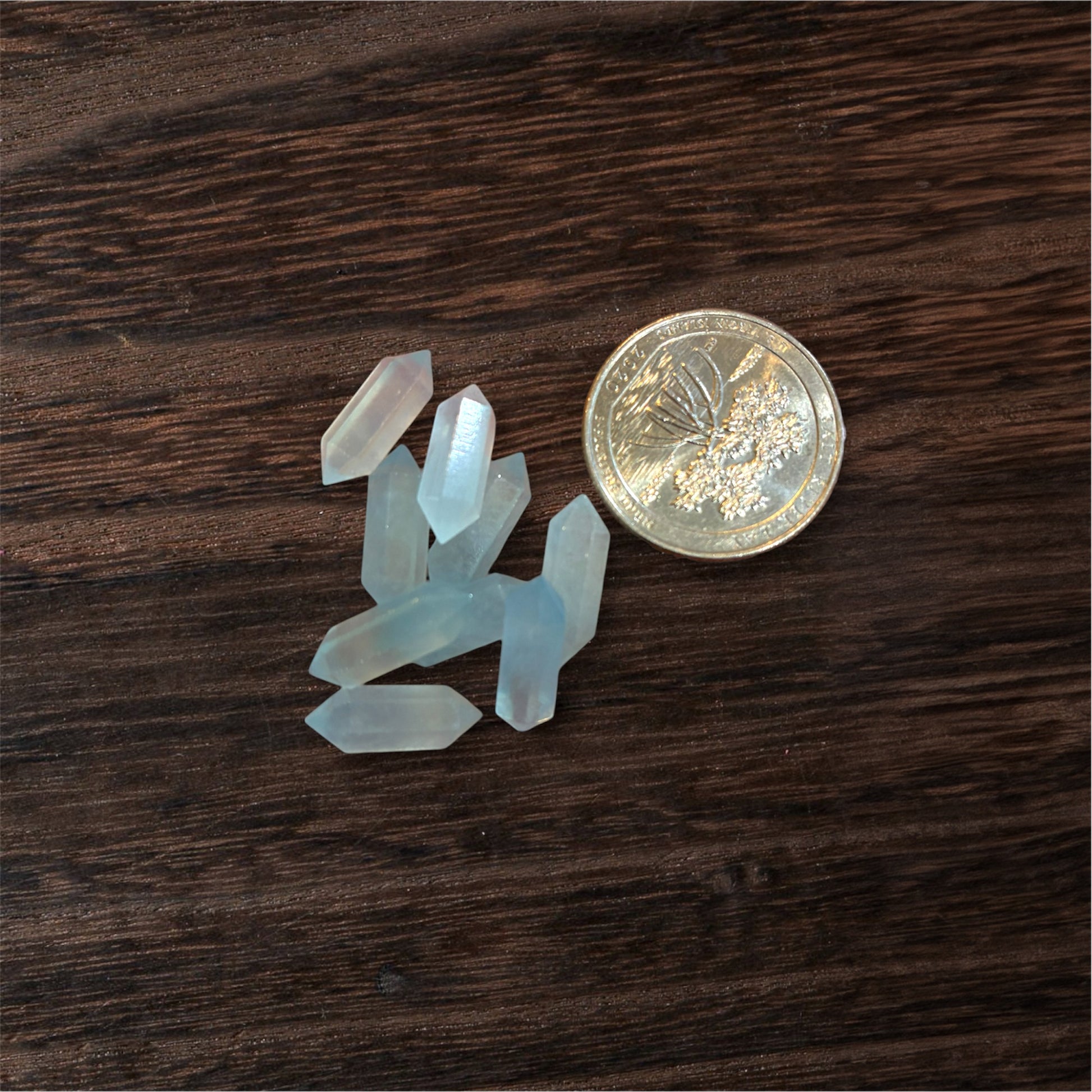 Small crystal formations next to a coin on a wooden surface