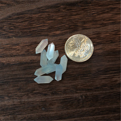 Small crystal formations next to a coin on a wooden surface