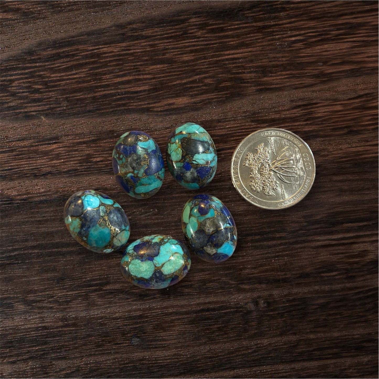 Turquoise stones on a wooden surface with a coin for scale