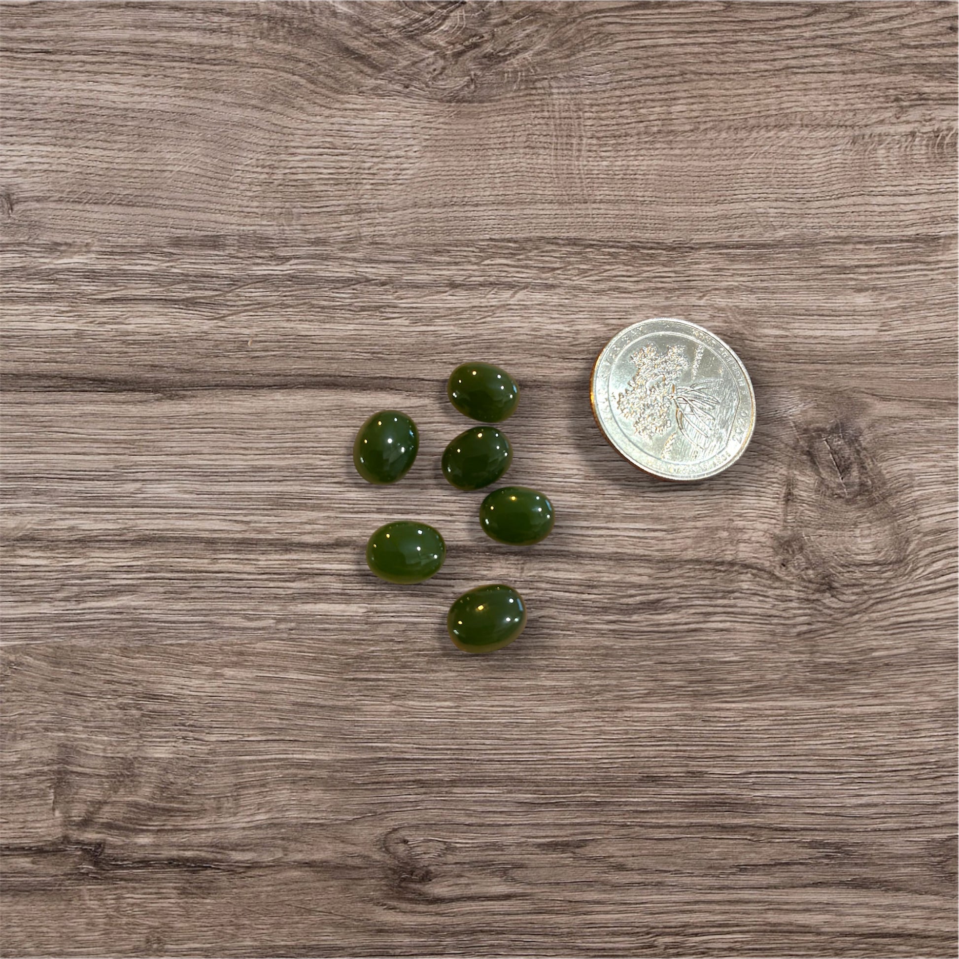 Green stones on a wooden surface with a coin for scale